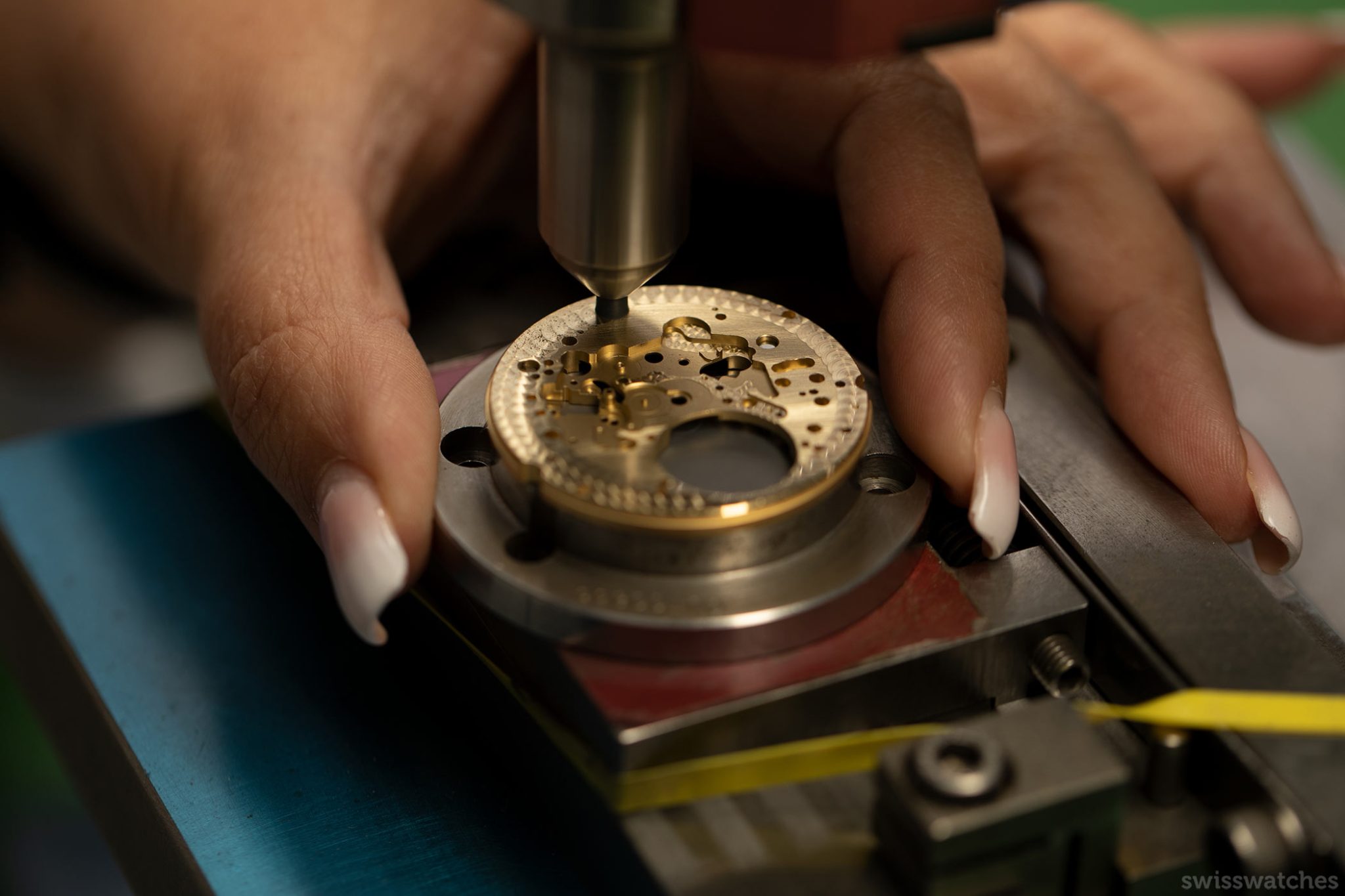 Another base of a dial being decorated with perlage through a specific machine
