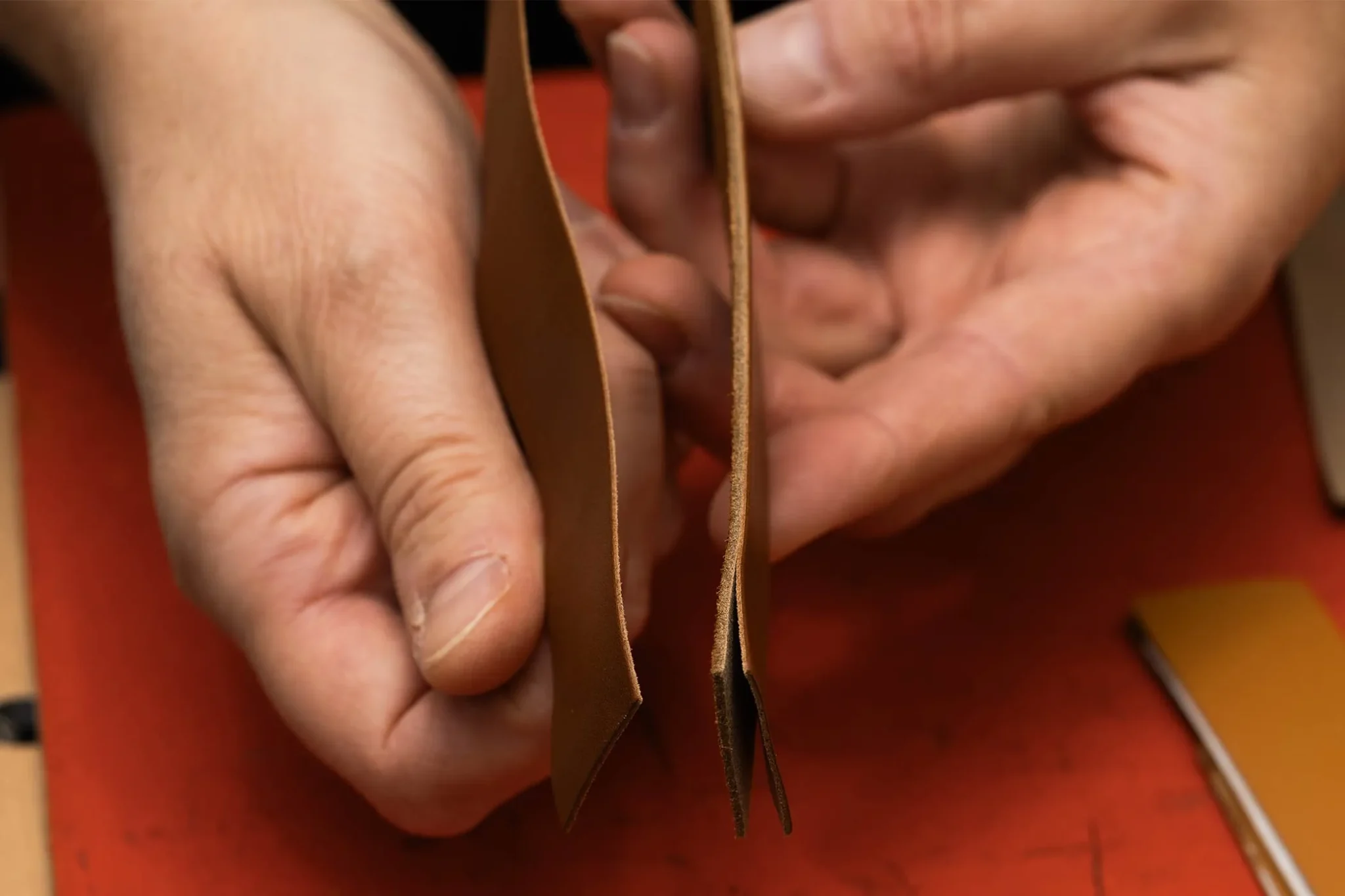 Skilled artisan splitting leather for a Hermès watch strap, showcasing precision craftsmanship in luxury watchmaking