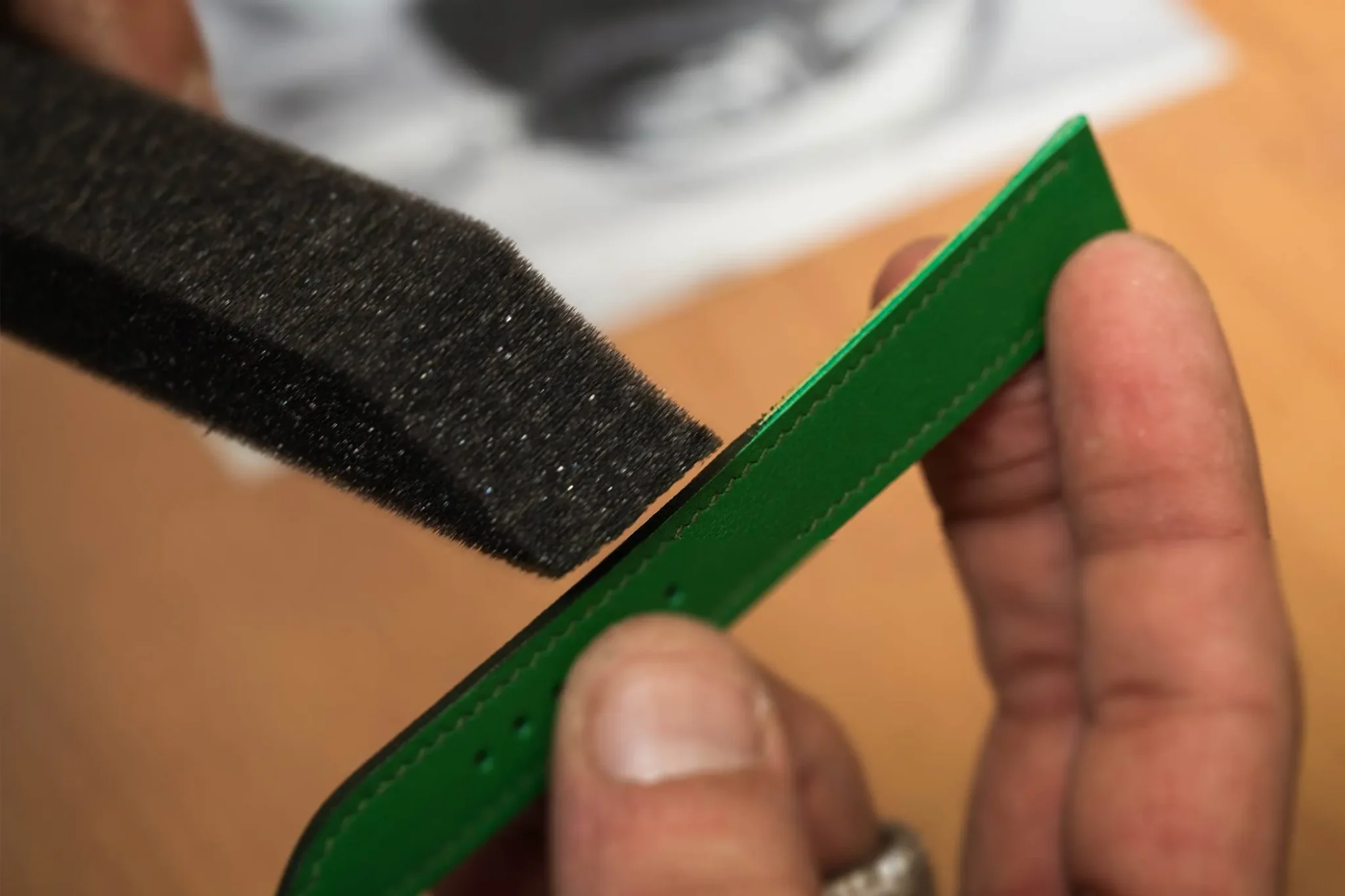 Artisan meticulously dyeing a Hermès watch strap, highlighting expert leather craftsmanship and luxury watchmaking techniques