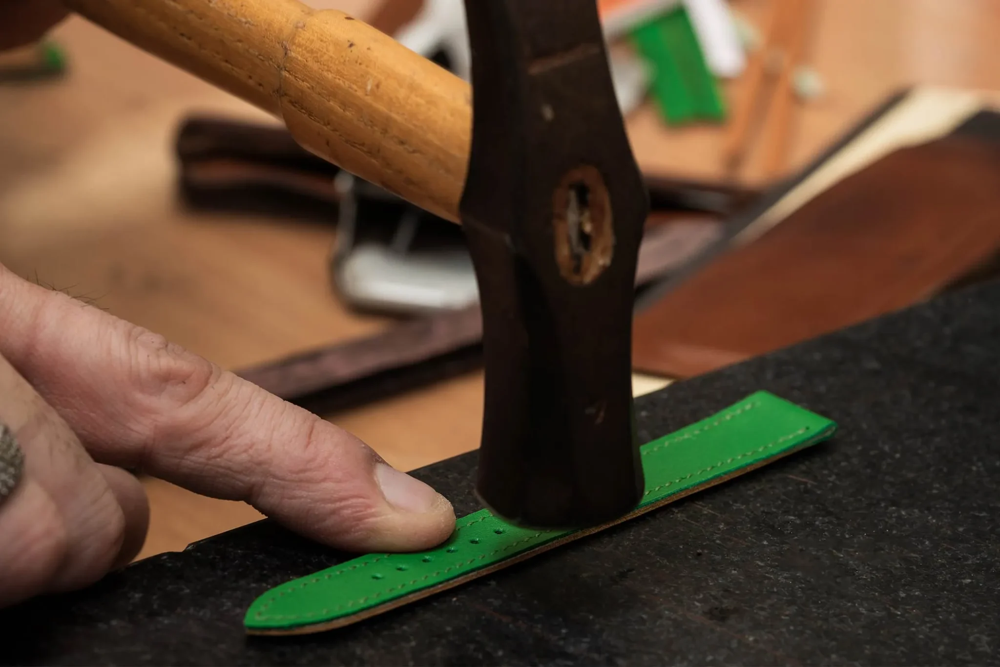 Expert artisan applying glue to a Hermès watch strap, showcasing luxury leather craftsmanship and precision in watchmaking