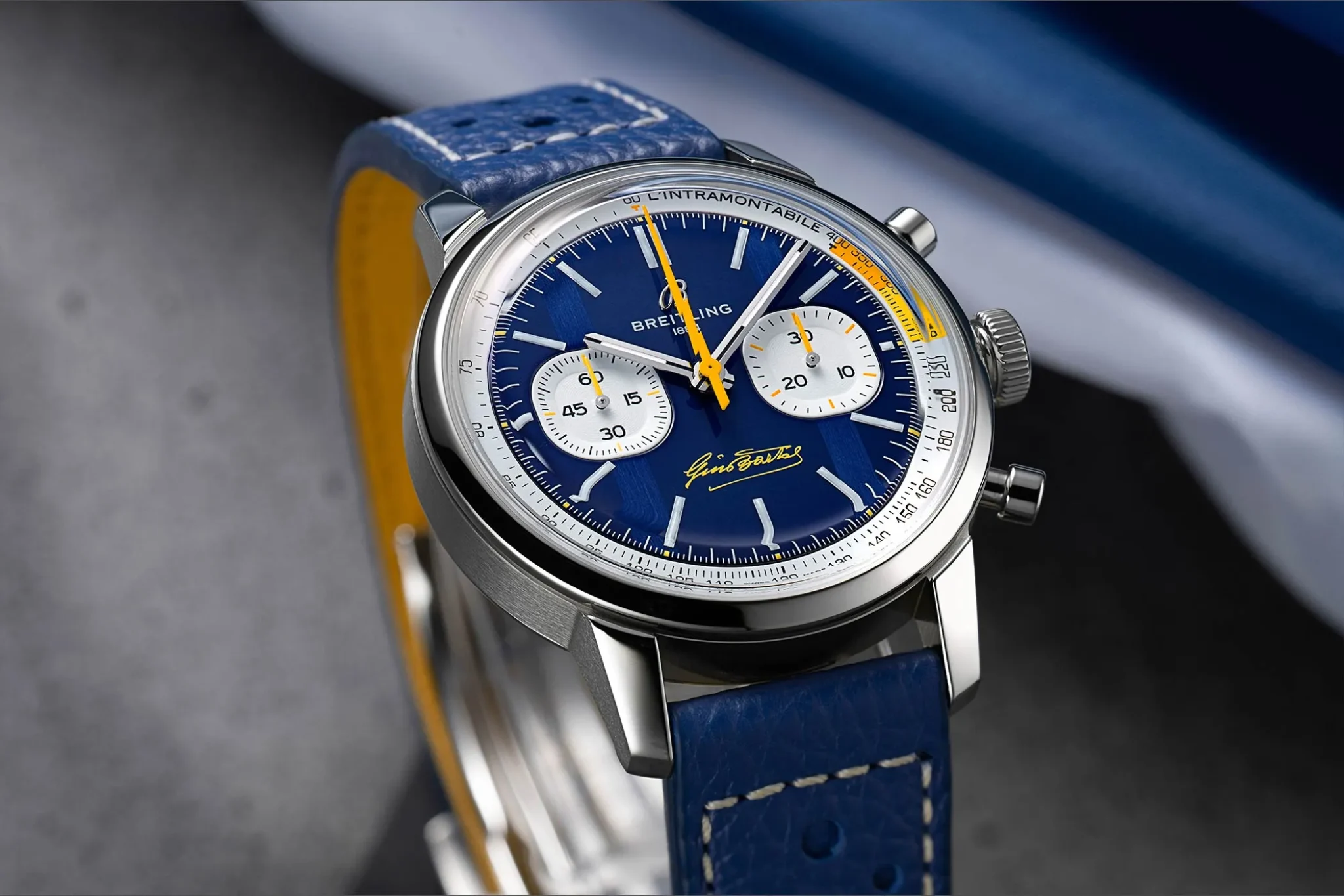 The blue dial of the Breitling Top Time B01 Gino Bartali has white counters and a yellow lightning-shaped second hand.