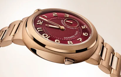 A close-up of the case of the Hermès Cut Le Temps Suspendu with red-tinted dial