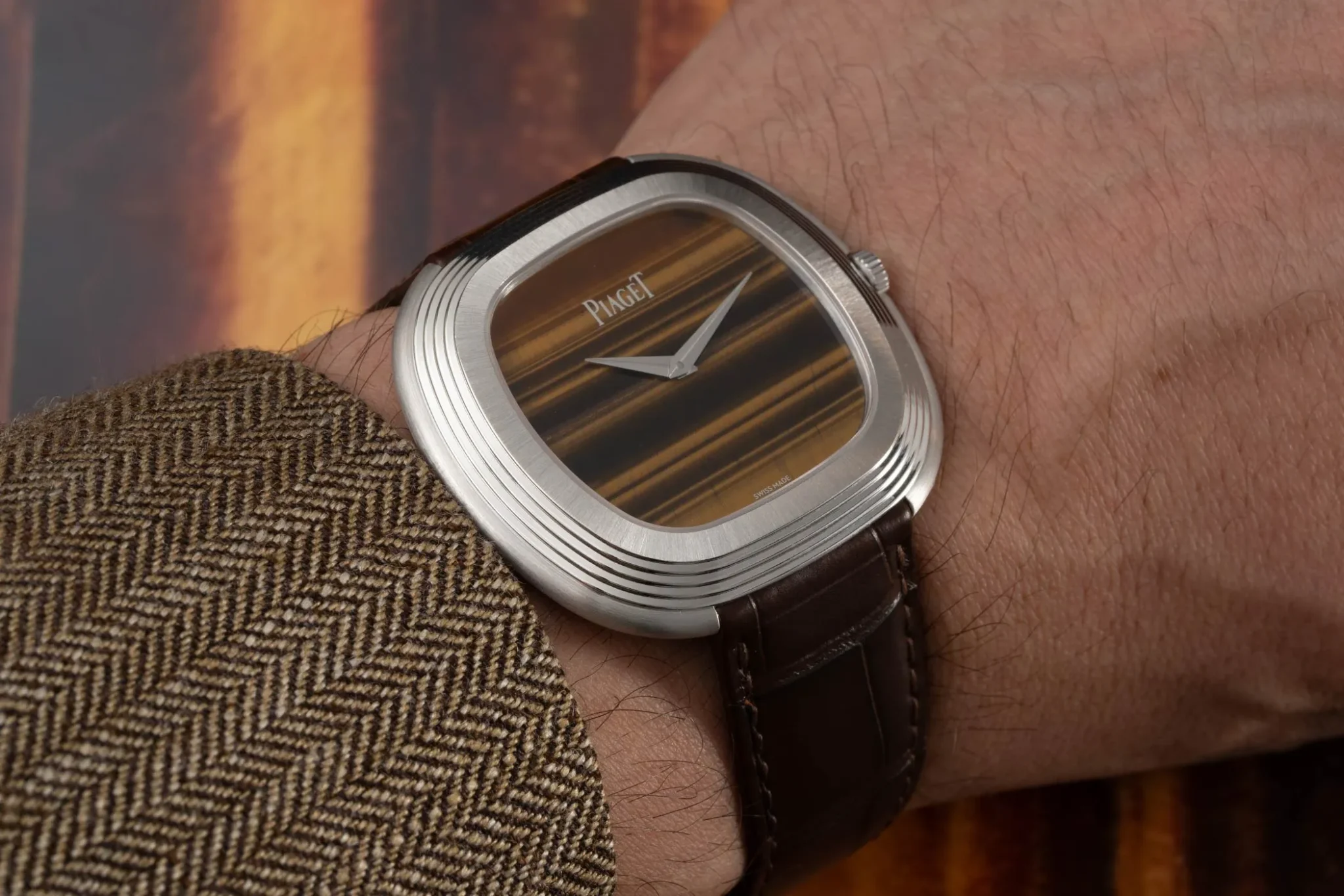 Wristshot of a Piaget Andy Warhol watch with a tiger's eye dial on a brown leather strap.