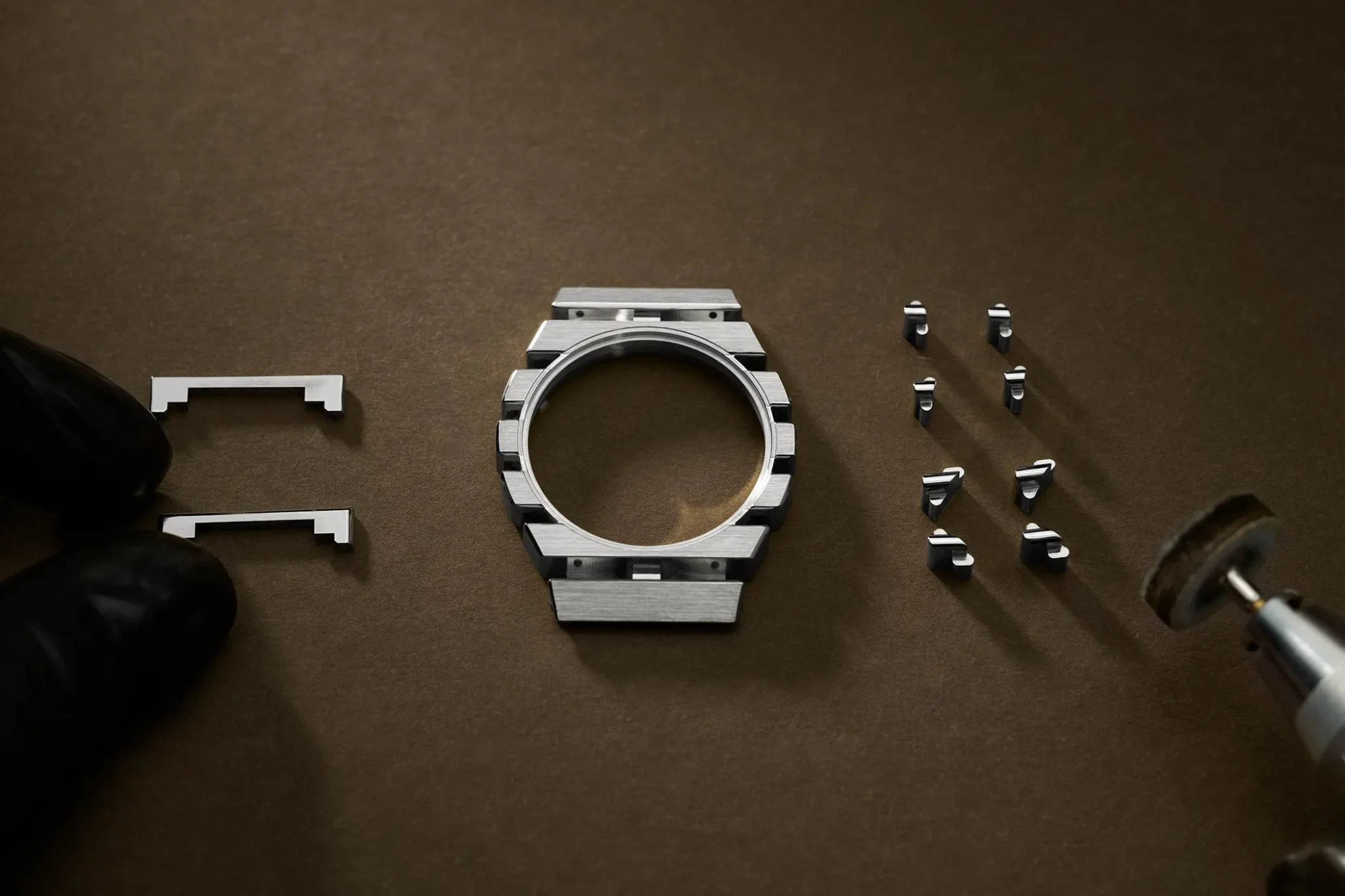 Piaget Polo 79 white gold watch case and components laid out with a polishing tool and gloved hands visible.