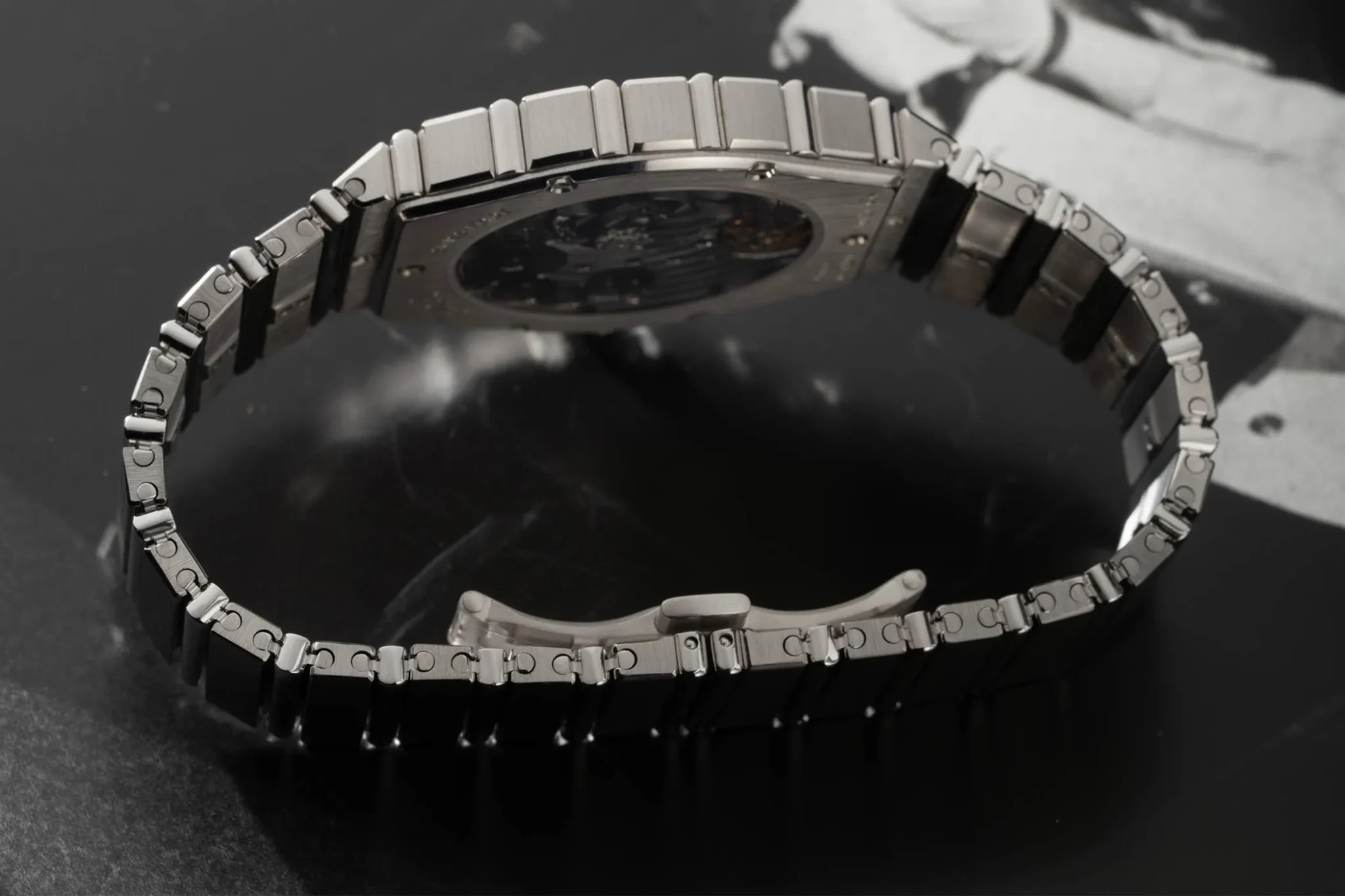 The Piaget Polo 79 white gold has an integrated white gold bracelet and is displayed lying on the side on a monochrome surface.