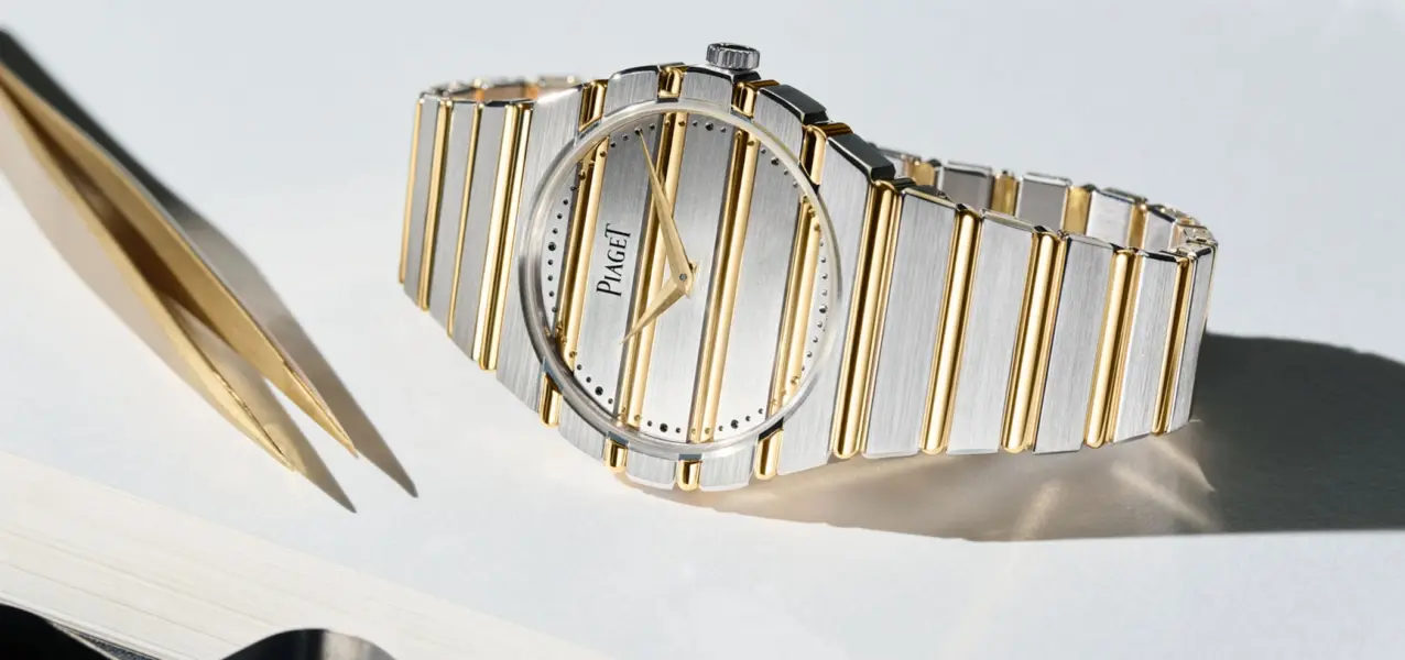 Piaget Polo 79 Two Tone lying on its side next to tweezers and a magnifying glass