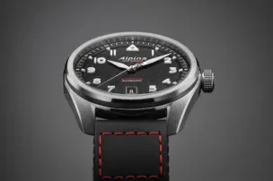 Close-up of the dial of the Alpina Startimer Pilot Automatic with black dial and black Cordura strap against a grey background.