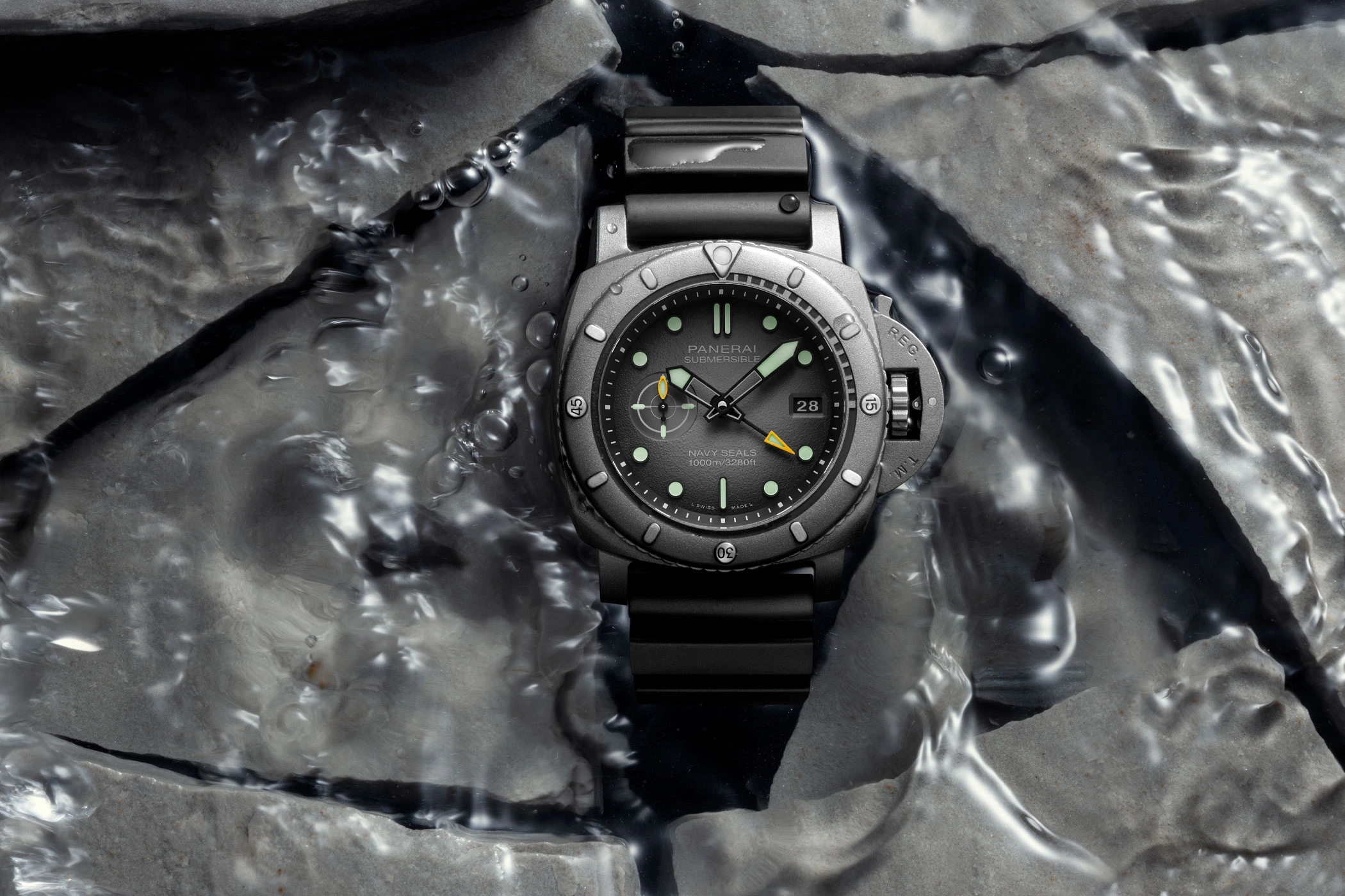 Panerai Submersible GMT Navy SEALs Afniotech Experience Edition PAM01089 on a water-covered surface of broken stone slabs