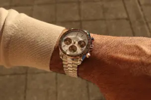 An Omega Speedmaster 38 mm from the 2026 model year, in a two-tone design featuring Sedna gold and a brown bezel, can be seen on the wrist.