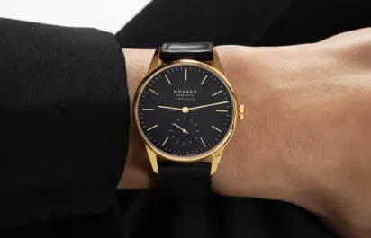 A Nomos Orion Gold neomatik new black can be seen on the wrist.