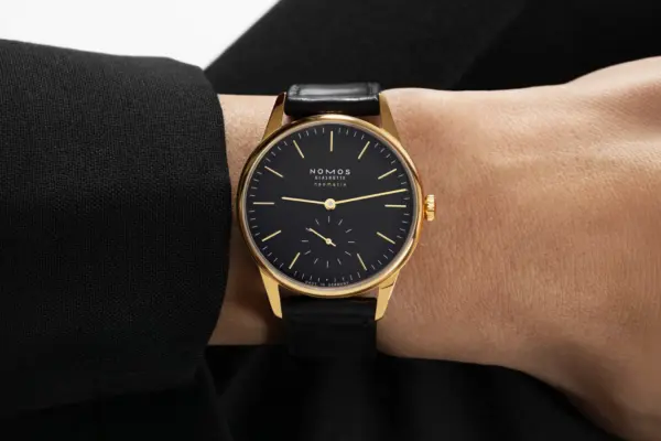 A Nomos Orion Gold neomatik new black can be seen on the wrist.