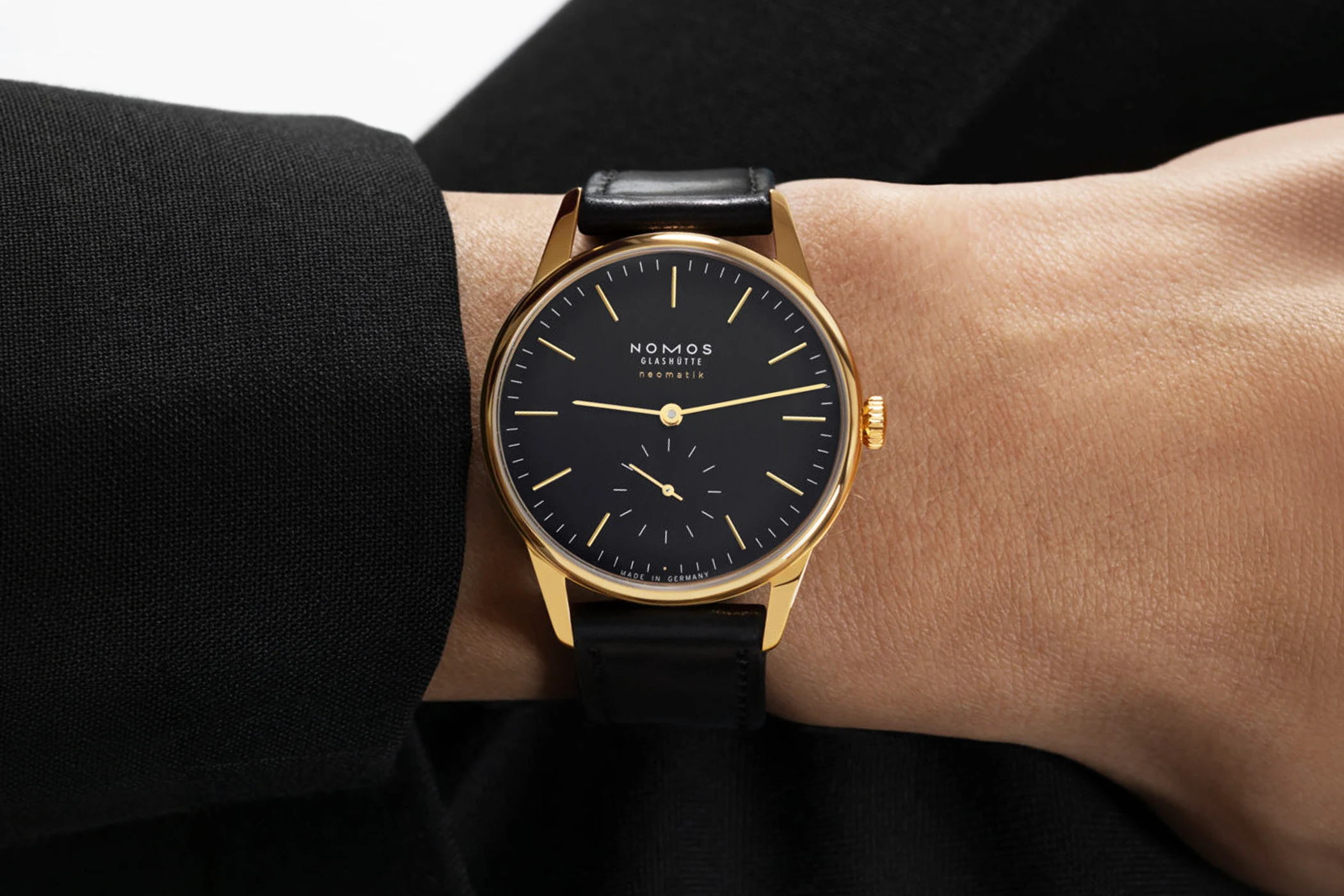 A Nomos Orion Gold neomatik new black can be seen on the wrist.