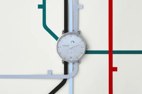The watch head of the Nomos Glashütte Metro Date Power Reserve Ice, shown against a stylized metro map.